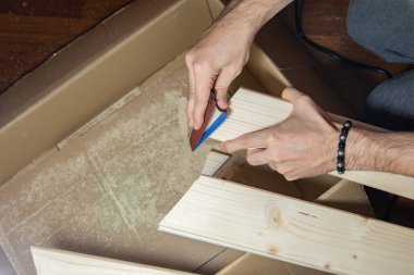 Bir adam evinde zımpara kağıdıyla ahşap bir tahtayı zımparalıyor, DIY