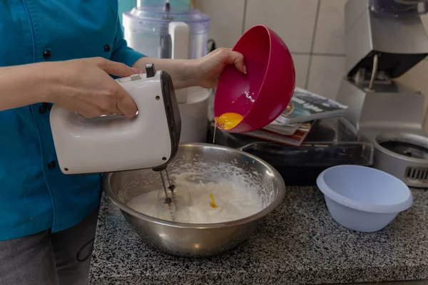 Kadın proteinleri metal bir kasede karıştırıcıyla dövüyor.