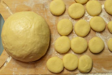 Hamur topu masanın üzerinde daireler halinde kesilmiş.