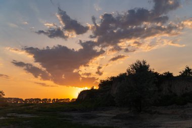 Tepenin arkasında altın bulutlarla gün batımı