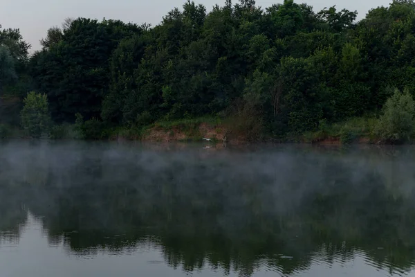 fog over the water of the lake forest is reflected in the water early in the morning before sunrise in summer