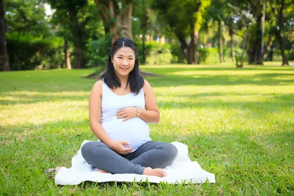 Beautiful pregnant asian woman reading the book in the park — Stock Photo, Image