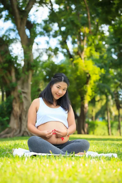 Beautiful pregnant asian woman reading the book in the park — Stock Photo, Image