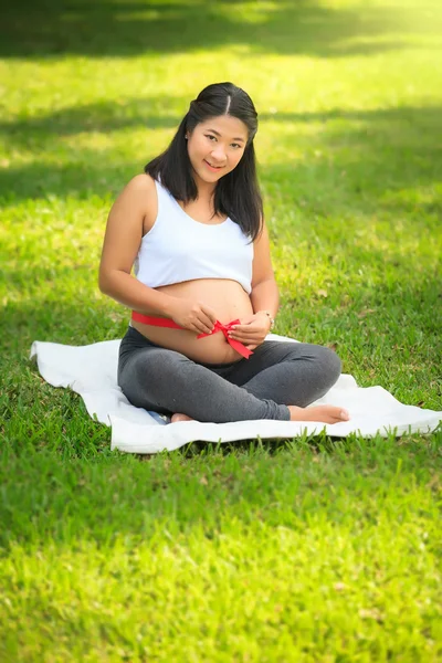 Beautiful pregnant asian woman reading the book in the park — Stock Photo, Image