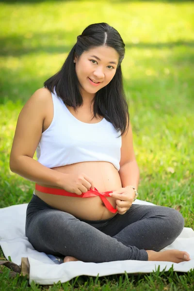 Beautiful pregnant asian woman reading the book in the park — Stock Photo, Image