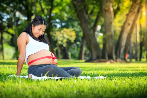 Beautiful pregnant asian woman reading the book in the park — Stock Photo, Image