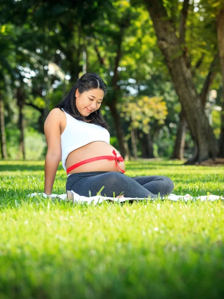 Beautiful pregnant asian woman reading the book in the park — Stock Photo, Image