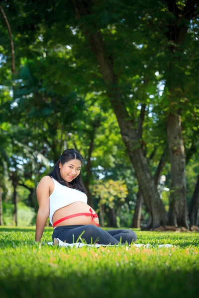 Beautiful pregnant asian woman reading the book in the park — Stock Photo, Image