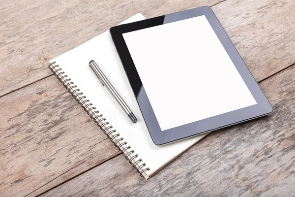 Tablet e bloco de notas em um desktop de madeira — Fotografia de Stock