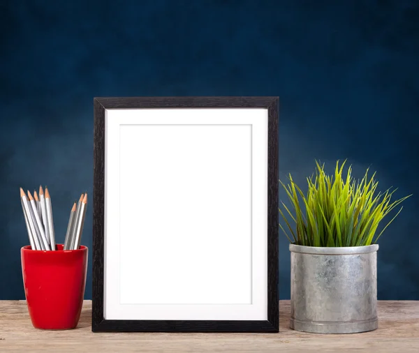 Moldura de imagem em fundo azul com itens de escritório e planta pote — Fotografia de Stock