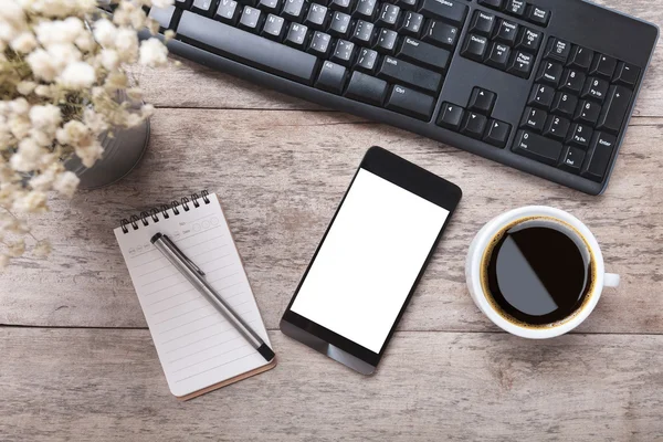 Arbetar bord med smart telefon Obs papper penna blommor och kopp — Stockfoto