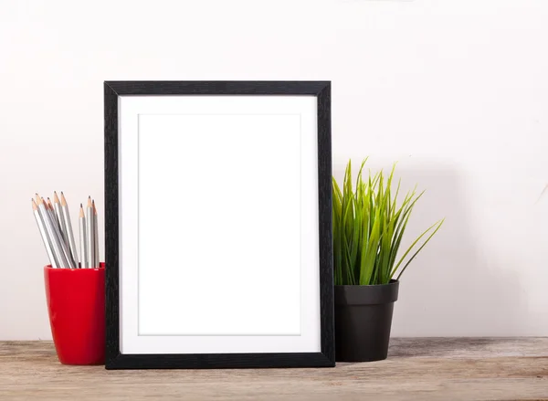Picture frame met kantoorartikelen en pot planr op houten tafel — Stockfoto