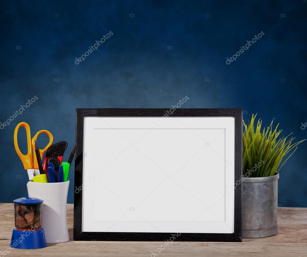 picture frame on blue background with office items and pot planr