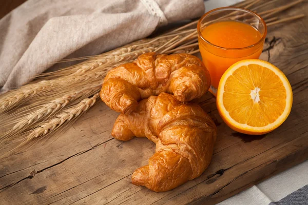 Tasty croissant and orange juice still life rustic — Stock Photo, Image