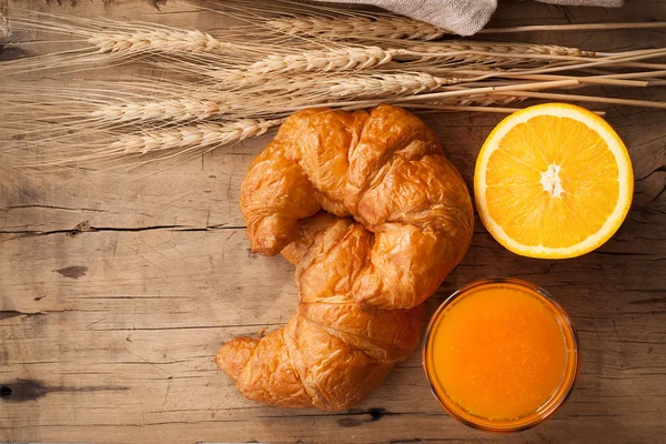 Tasty croissant and orange juice still life rustic — Stock Photo, Image