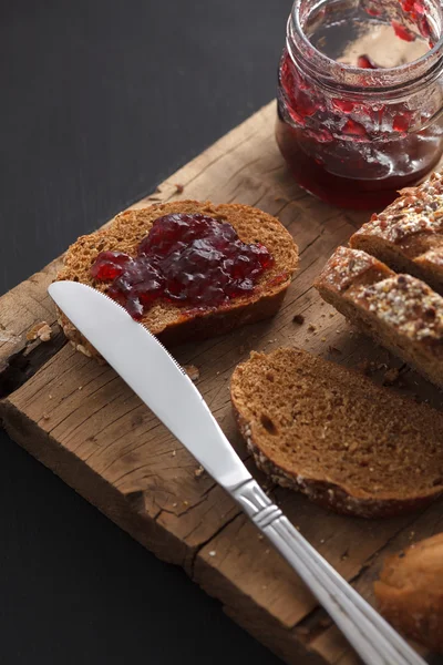 Dunkles Mehrkornbrot Vollkornbrot und Marmelade frisch gebacken auf rustikalem — Stockfoto