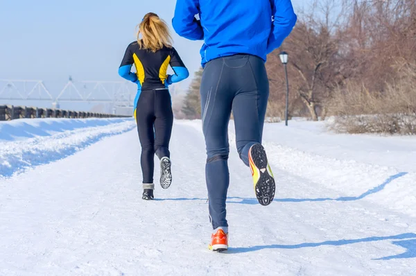 Corridori. Gambe, vista posteriore. Giovani coppie in corsa. Sport uomo & donna jogging sul parco invernale Foto Stock Royalty Free