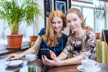 İki güzel genç kadın café outsi yılında telefon SMS okuma