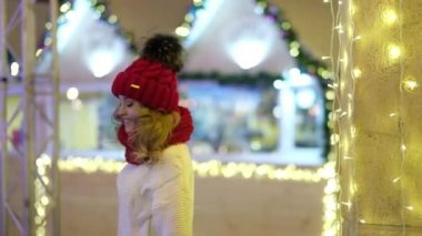 Noel festivalinde çelenkleri ve tatil ışıklarıyla gülümseyen kadın.