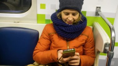 Kadın yolcu metroda cep telefonu kullanıyor..