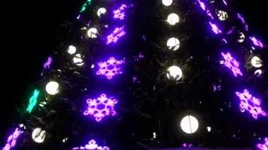 Süslü Noel süslerinin yakın çekimi. Noel ağacında çelenkler, toplar ve ışıklar