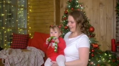 Mutlu anne Noel ağacının yanında bebekle oynuyor.