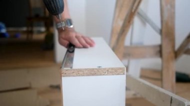 Yaşlı adam mobilya sondajı yapıyor. Evdeki yenileme işlerinde sondaj yapıyor.