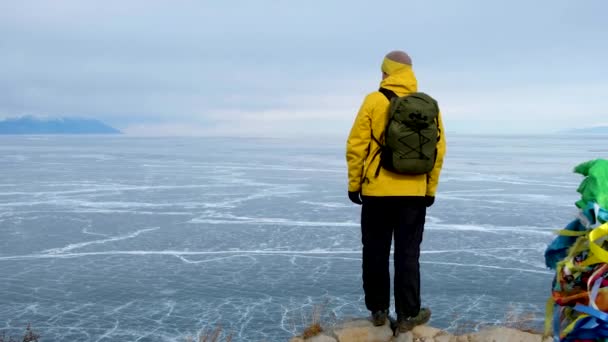 Турист поднимается на вершину и смотрит на лед Байкала. Ледяное озеро — стоковое видео
