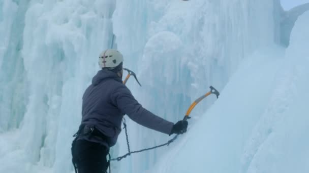 Alpinista s nářadím na led šplhá po velké ledové stěně. — Stock video