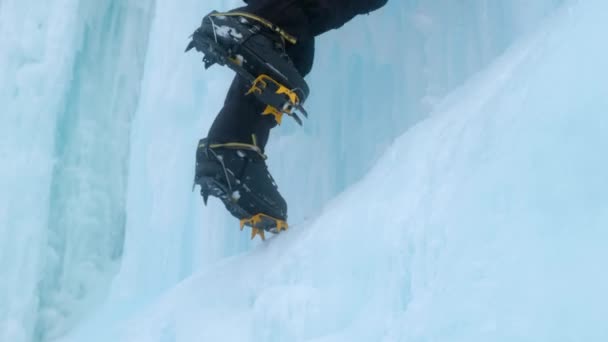 Кошки крупным планом на ногах ледолаз на замерзшем водопаде. Осколки льда. — стоковое видео
