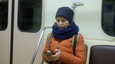 Kadın yolcu metroda cep telefonu kullanıyor..
