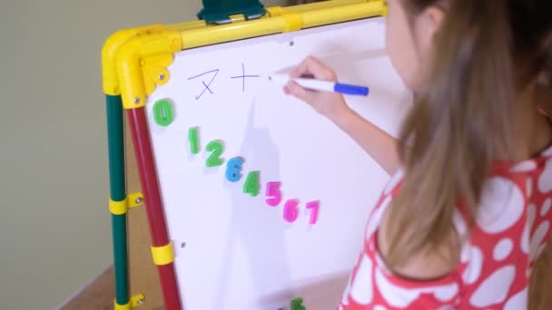 Девочка, использующая магнитную доску для изучения букв и цифр дома — стоковое видео