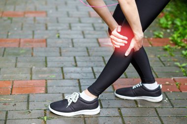 Kadın atlet, dizine acı içinde dokunuyor, kadın sporcu yaz parkında koşuyor. Sağlıklı yaşam tarzı ve spor anlayışı.