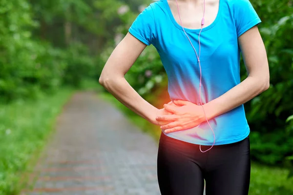 Side pain - woman runner side cramps after running. Jogging woman with stomach side pain after jogging work out. Female athlete.