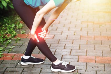 Kadın atlet, dizine acı içinde dokunuyor, kadın sporcu yaz parkında koşuyor. Sağlıklı yaşam tarzı ve spor anlayışı.