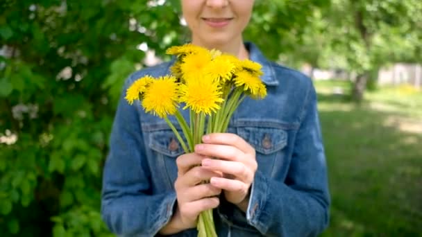 Wanita tersenyum memegang karangan bunga dandelion. Wanita dan bunga liar kuning — Stok Video