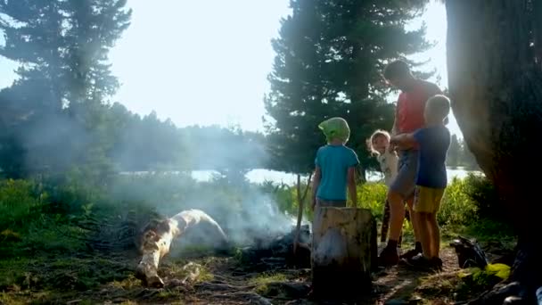家族のキャンプ。キャンプファイヤーで料理をする父と3人の子供 — ストック動画