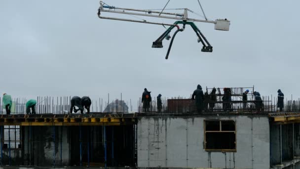 NOVOSIBIRSK, RUSSIA - 14 juli 2020: Byggnadsarbetare häller våt betong med hjälp av betongspindelslang eller pumpning på höghus. arbete i regn — Stockvideo