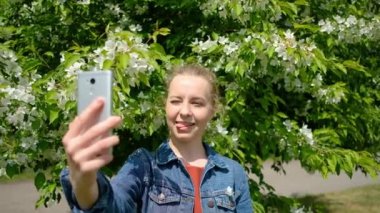Yeşil bahar çiçek parkında selfie çeken güzel bir kadın.
