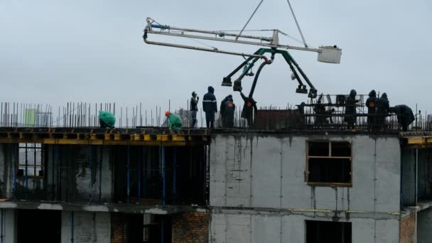 ロシアのノヴォシビルスク- 2020年7月14日:コンクリートのクモの巣やポンプの作業場を使用してコンクリートを濡らしたコンクリートを注ぐ建設労働者。雨の中で — ストック動画