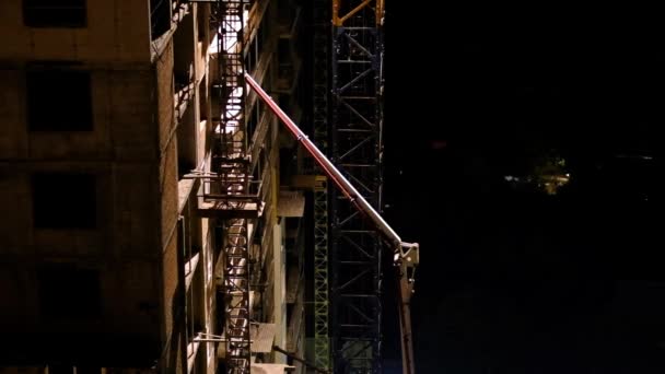 Trabajadores de la construcción vertiendo hormigón húmedo utilizando manguera de araña de hormigón o trabajo de bomba en el sitio de gran altura en la noche — Vídeo de stock