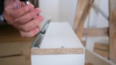 Yaşlı adam mobilya sondajı yapıyor. Evdeki yenileme işlerinde sondaj yapıyor.