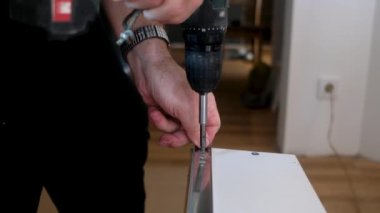 Yaşlı adam mobilya sondajı yapıyor. Evdeki yenileme işlerinde sondaj yapıyor.