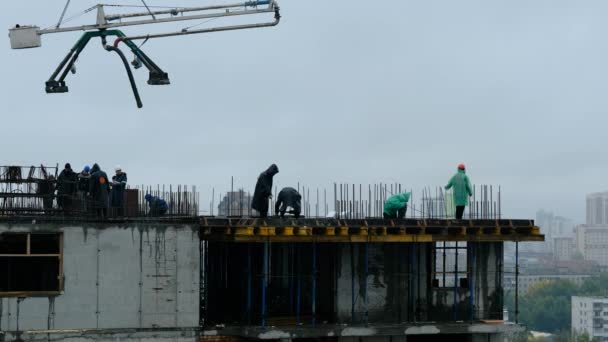 NOVOSIBIRSK, RUSSIA - 14 Temmuz 2020: İnşaat işçileri yüksek binalarda beton örümcek hortumu ya da pompa ile ıslak beton döküyorlar. Yağmurda çalışmak — Stok video