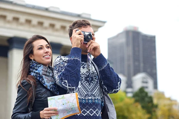 Gezintide ya da şehir turunda fotoğraf çeken mutlu bir çift turist. Bir harita ve retro kamerayla birlikte seyahat edin. — Stok fotoğraf