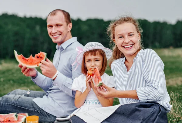 ピクニックで幸せな家族スイカを食べている 草原や公園のピクニックで母と父と子 — ストック写真