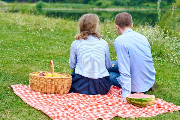 这对年轻夫妇在野餐时坐在红色的房间里的桌布上 在大自然的草地或公园休息的情侣 — 图库照片