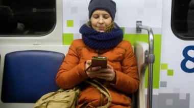 Kadın yolcu metroda cep telefonu kullanıyor..