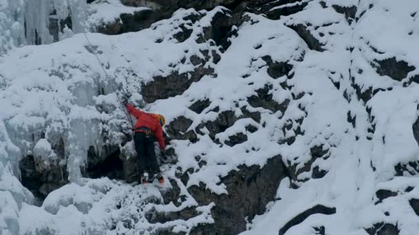 Alpinist man med is verktyg yxa klättra ett fruset vattenfall, en stor vägg av is — Stockvideo