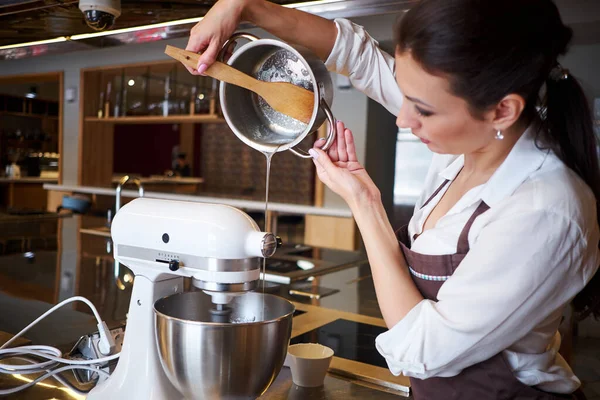 Femme Utilisant Mélangeur Debout Comptoir Dans Son Tablier Faire Dessert Image En Vente